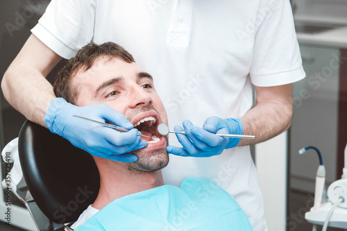 Dentist examines the teeth of a male patient on a dentist s chair. Copy  empty space for text