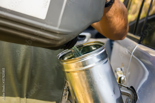 male worker adds an additive to diesel fuel. Increase combustion efficiency. A male hand pours fuel into a car from a canister.