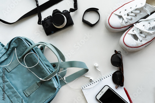 Items for a great vacation lie on a white background photographed from above, a blue backpack for urban lifestyle