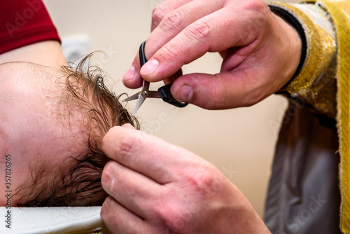 Priest cuts baby's hair during baptism.