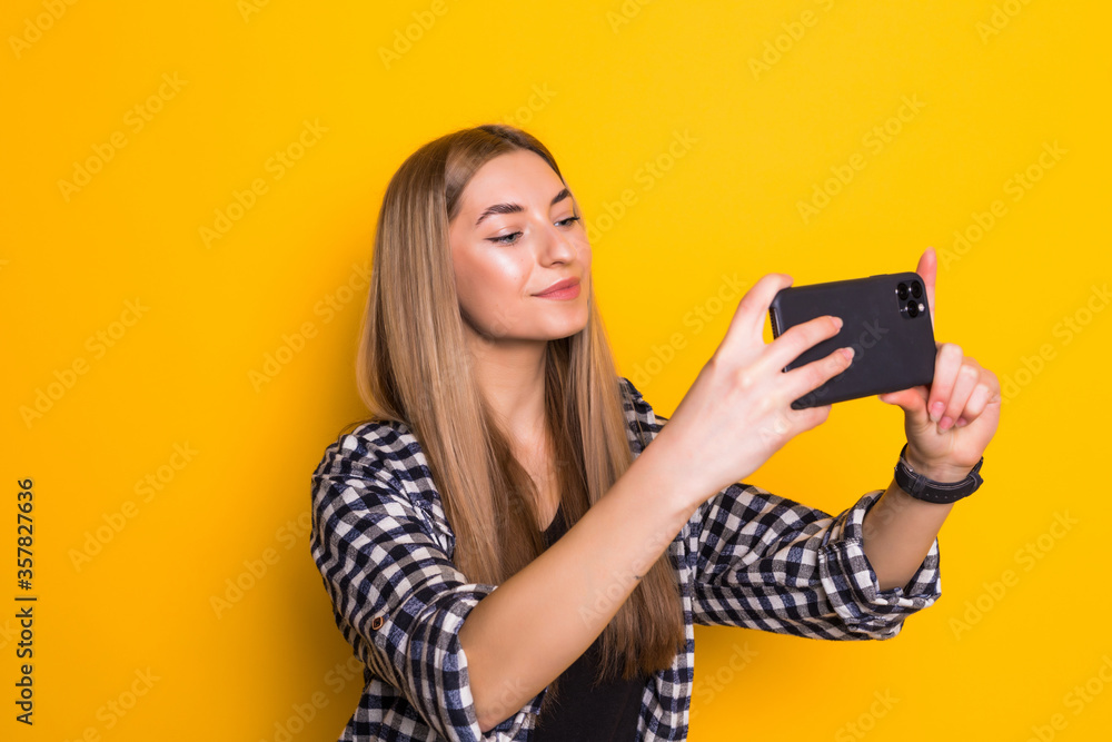 Fashionable young girl take selfie on the phone posing on yellow background, Fashionable young girl take selfie on the phone posing on yellow background,