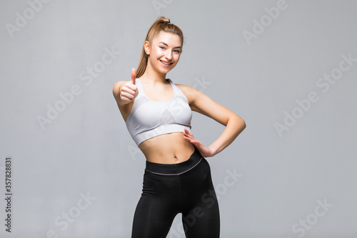 Happy fitness young woman showing thumbs Up on gray background © dianagrytsku