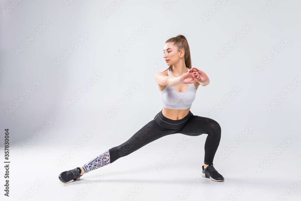 Obraz premium Fitness woman doing stretching workout. Full length shot of young woman on white background. Stretching and motivation
