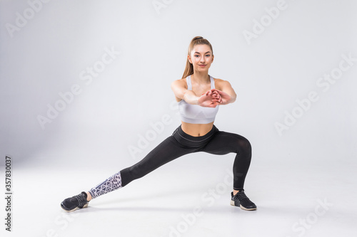 Fototapeta Naklejka Na Ścianę i Meble -  Fitness woman doing stretching workout. Full length shot of young woman on white background. Stretching and motivation