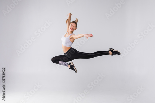 Happy young fitness woman jumping over white background