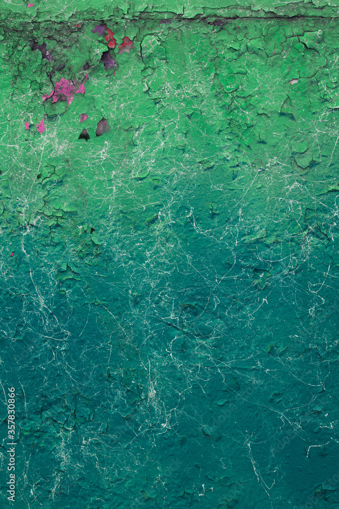 Obraz premium The texture of cracked green paint in different shades with pink spots and white stains. The vertical photo for your urban design.
