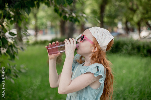 Photography Red-haired child drinks water from a plastic bottle