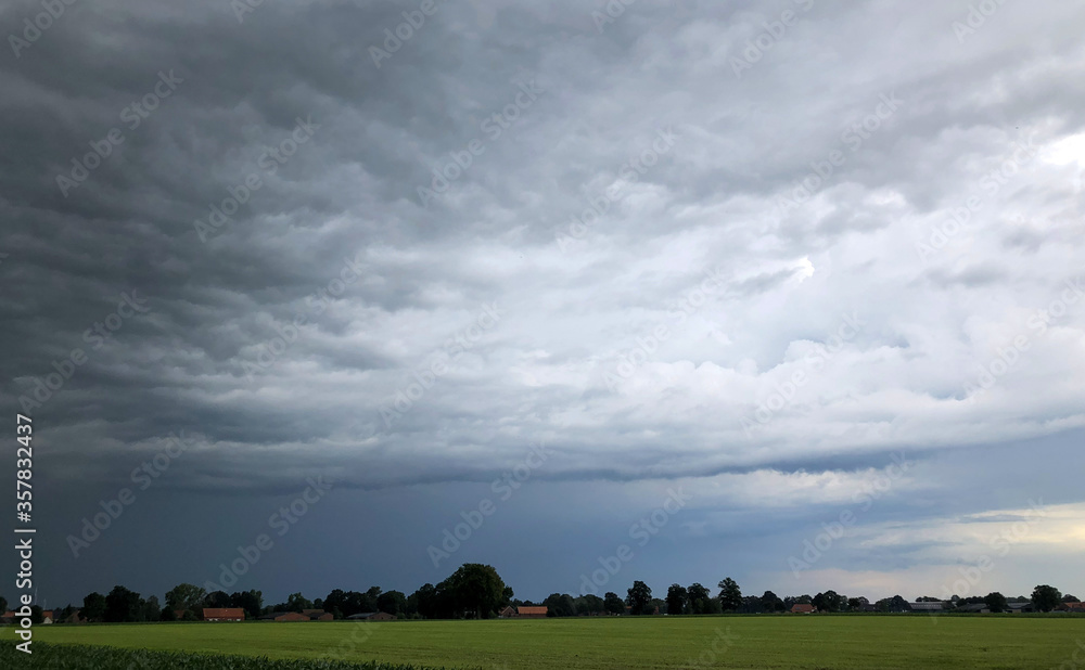 Threatening dark rainy clouds are covering a rural landscape, showing the Overcast and gloomy sky above the countryside creating a beautiful and impressive dramatic scenery Threatening dark rainy clouds are covering a rural landscape, showing the Overcast and gloomy sky above the countryside creating a beautiful and impressive dramatic scenery