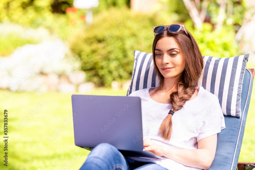 Young woman working on laptop in the garden Young woman working on laptop in the garden