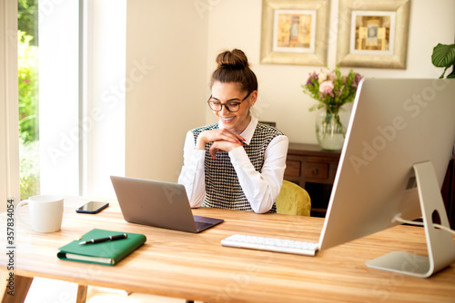 Happy young woman using her notebook while working from home