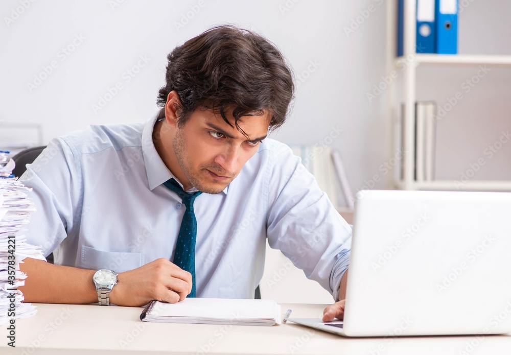 Overloaded busy employee with too much work and paperwork Overloaded busy employee with too much work and paperwork