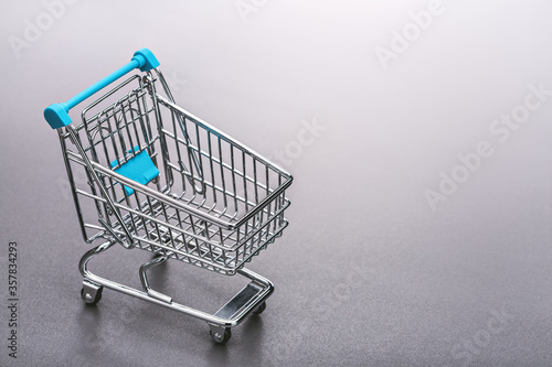 Metal shopping cart (toy). Gray background, copy space.