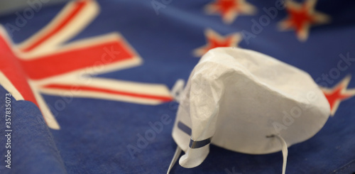 A crumpled face mask discarded after New Zealand successfully beats the covid-19 corona virus allowing public life to return to normal. New Zealand flag proudly in the background.