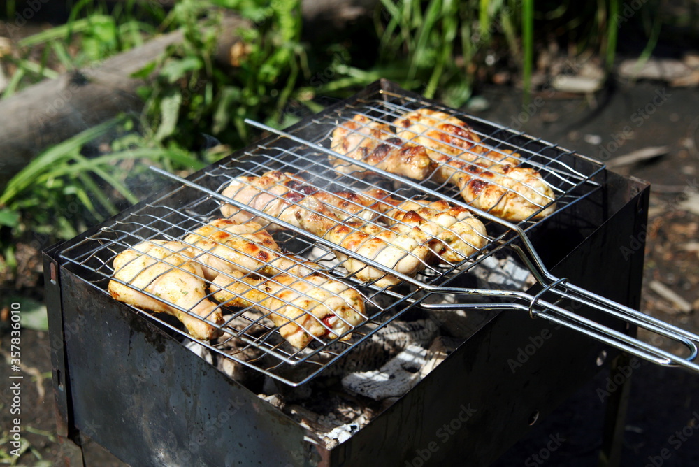chicken legs are grilled on the grill in nature