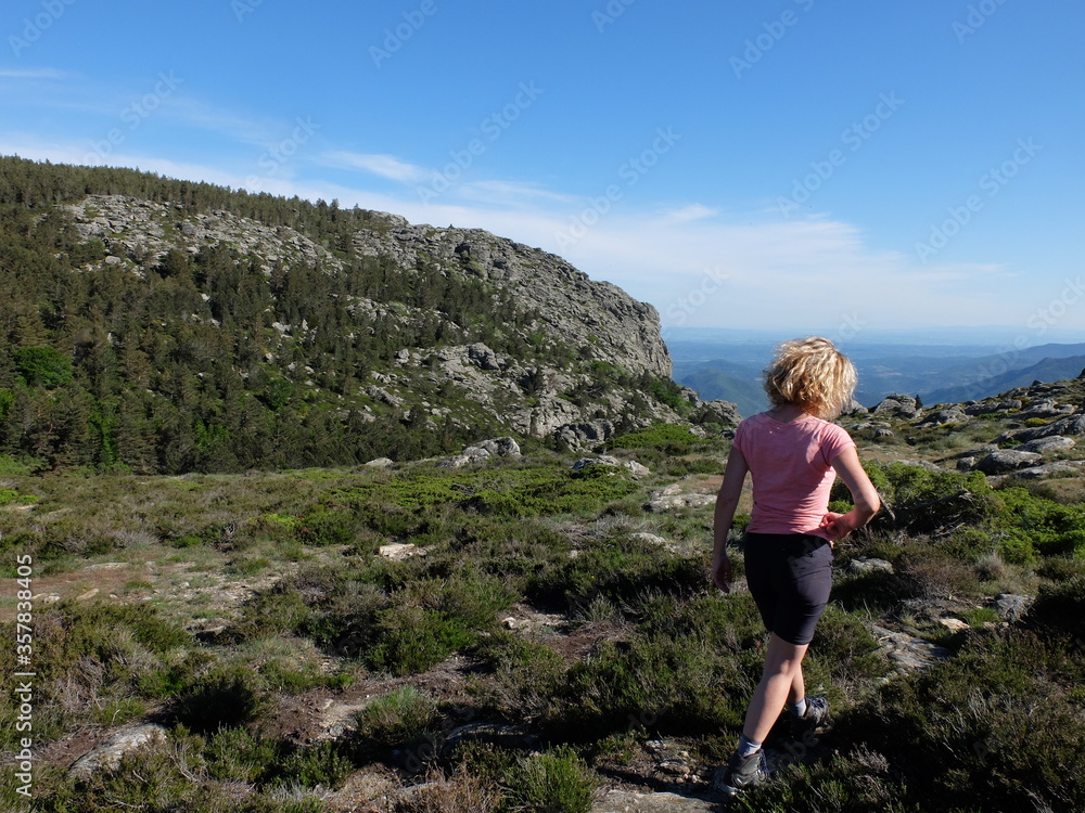Jeune femme marchant en randonnée sur le plateau de montagne du Caroux du parc naturel régional du Haut Languedoc