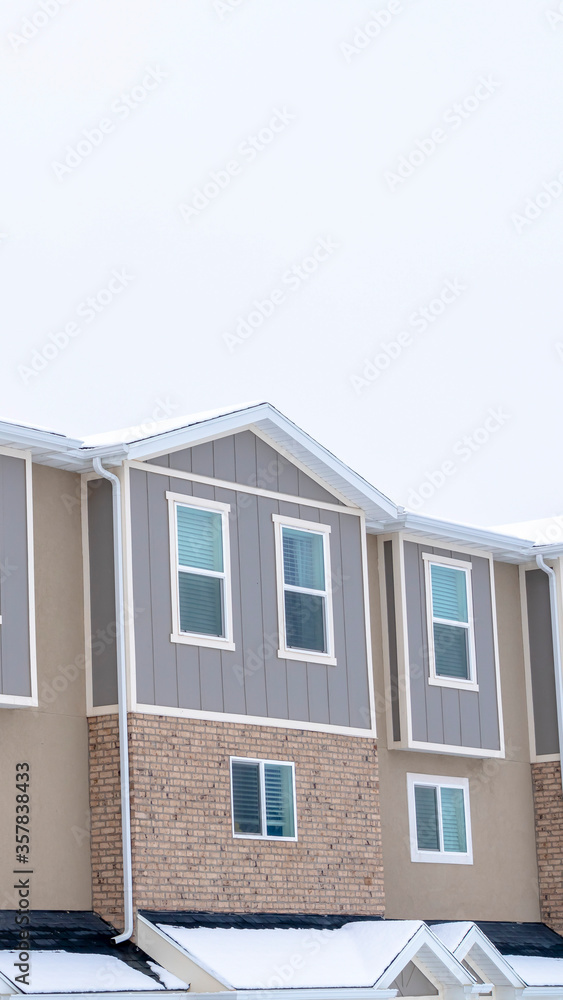 Vertical Upper storey of townhomes with snowy pitched roofs on a cold winter day