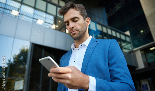 Young businessman reading a text message on his cellphone
