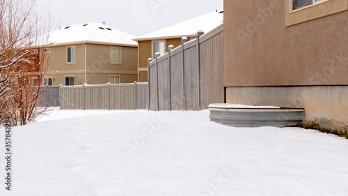 Panorama Ground blanketed with snow in front of houses and woodne fence in winter