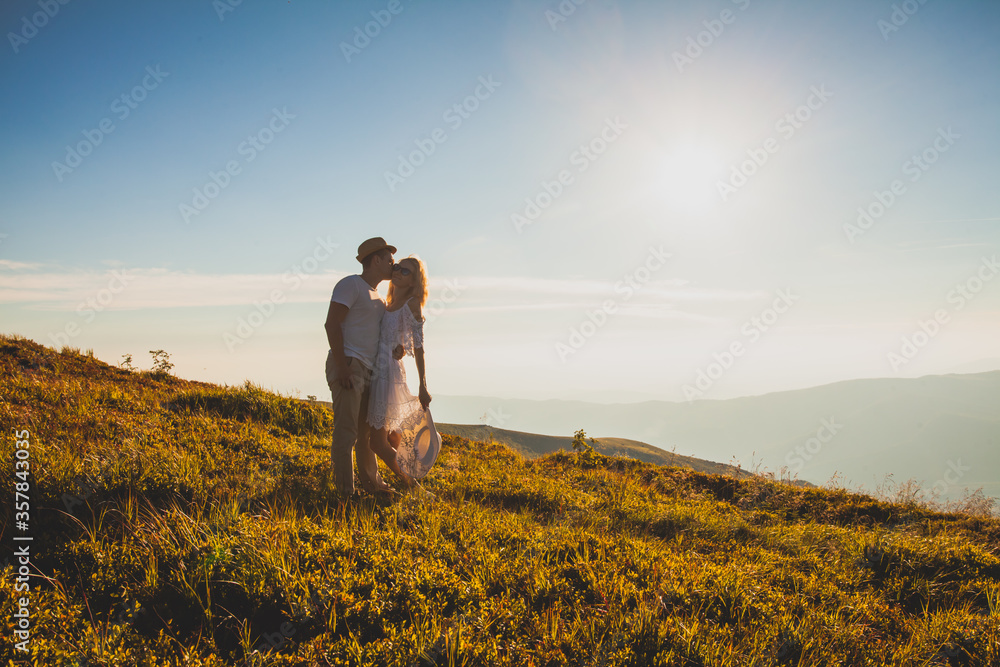 Embracing romantic couple in white on a hill