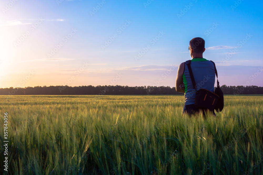 A man stands in the middle of a field and looks at the sunset A man stands in the middle of a field and looks at the sunset
