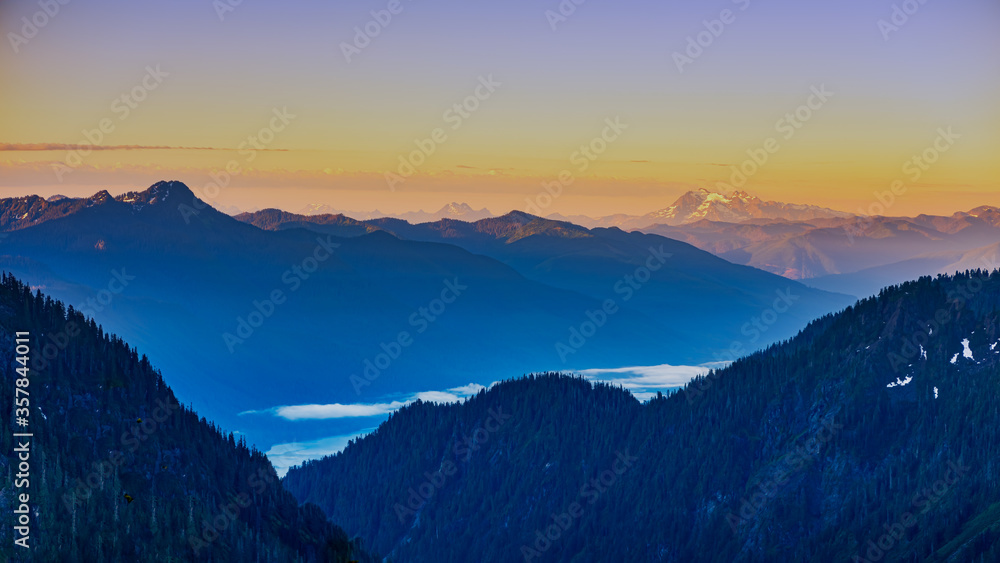 Alpine vista with clouds lake and mountains at sunrise