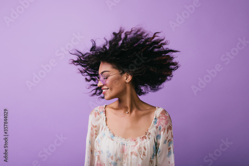 Studio photo of inspired african lady dancing with eyes closed. Indoor portrait of relaxed black girl isolated on purple background.