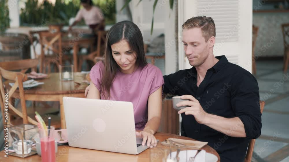 Freelancers, man and woman work in cafe, use laptop, discuss project Freelancers, man and woman work in cafe, use laptop, discuss project