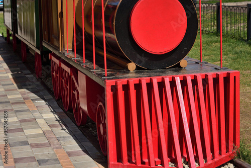 A model of a steam locomotive made of wood painted in bright color in a city park