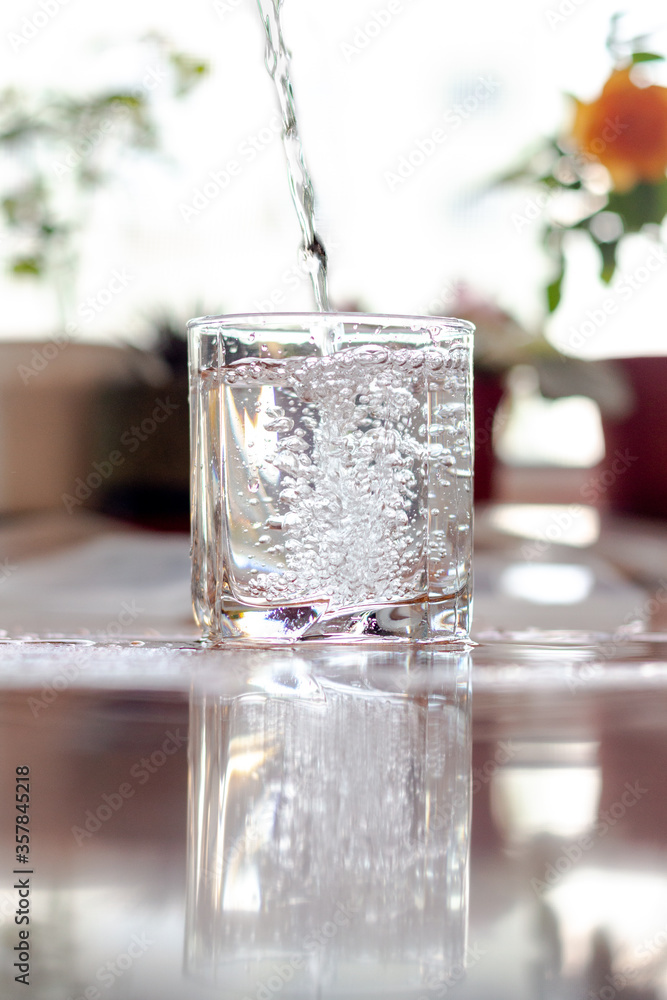 Pouring cold clean water into a glass goblet on a sunny, hot day. Pouring cold clean water into a glass goblet on a sunny, hot day.