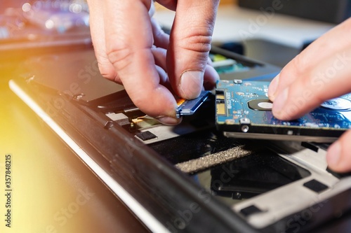 Installing hdd on an old laptop, on a black background with flare light. Concept of upgrading a laptop computer. Close up view