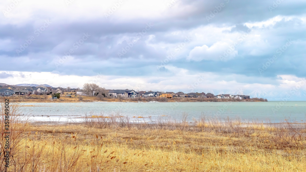 Panorama Scenic lake landscape with residences by the shore beneath sky with puffy clouds