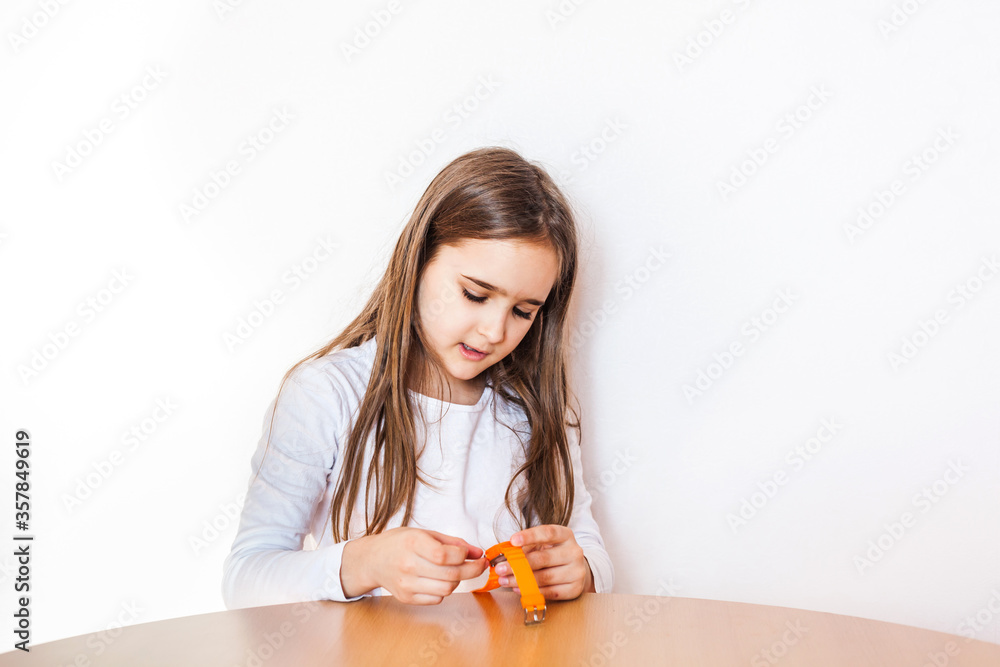 Girl school girl sitting at the table setting the clock, clock on hand, girl, time, child Girl school girl sitting at the table setting the clock, clock on hand, girl, time, child