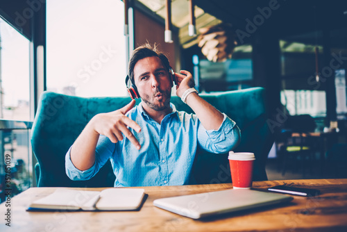 Emotional male enjoying stereo music during leisure time in coffee shop