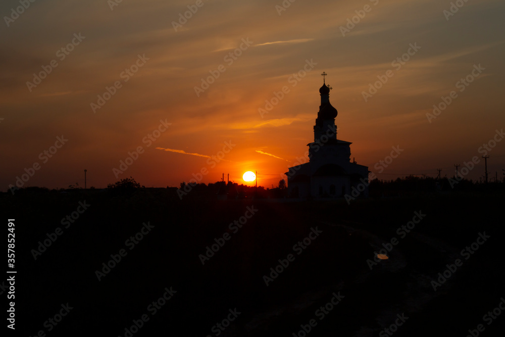Beautiful evening view of the silhouette of an Orthodox church in a field at sunset in Russia Moscow Region
