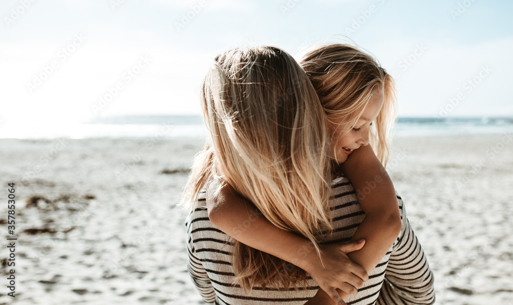 Mother carrying daughter along the beach