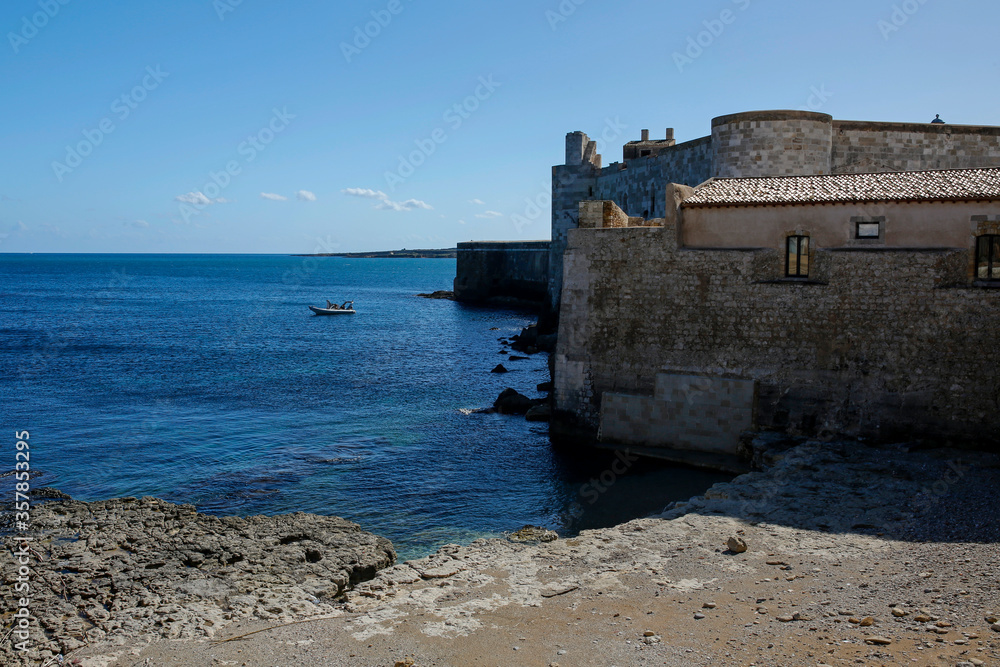 seashore and Maniace Castle on Island of Ortigia, oldest part of the beautiful baroque city of Syracuse in Sicily, Italy