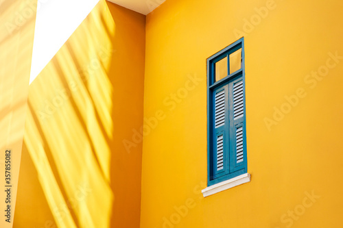 Colorful vintage building with blue window on yellow wall in morning with sunshine