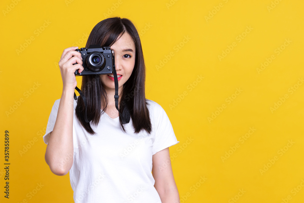 Fototapeta premium Asian woman smiling pretty girl in white shirt taking photo on camera isolated over color background