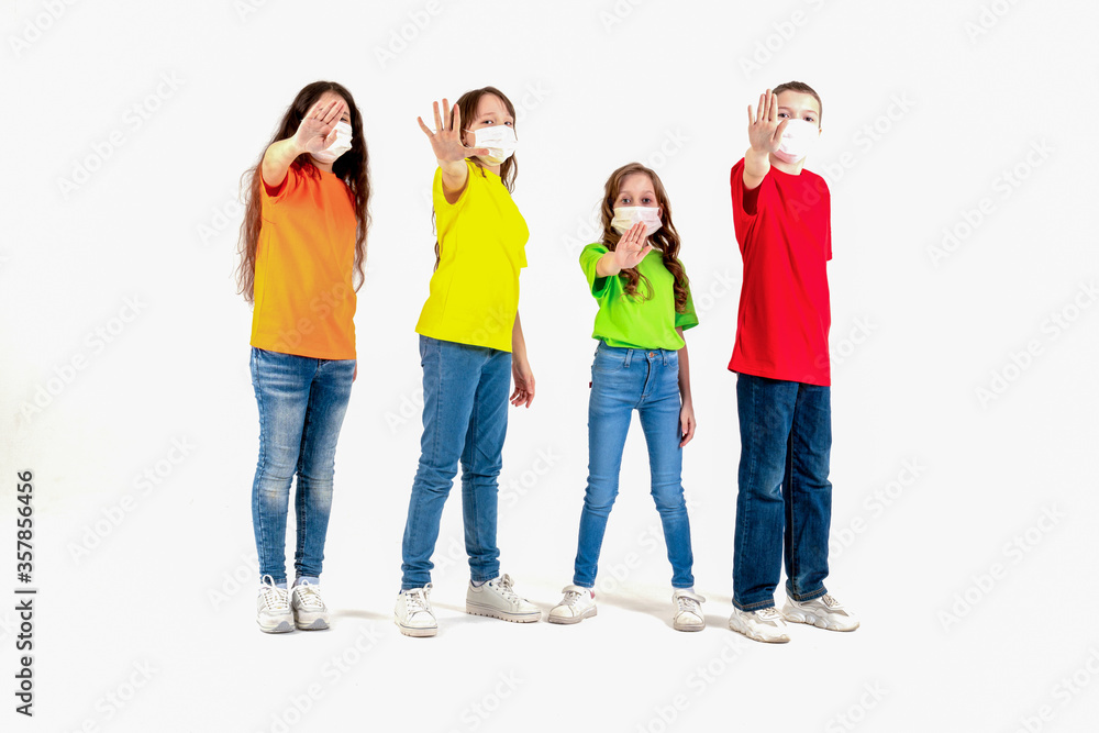 Group of schoolchildren children in colorful T-shirts and medical masks showing crossed hands gesture while looking at the camera over white background. Isolated. Stay at home. Group of schoolchildren children in colorful T-shirts and medical masks showing crossed hands gesture while looking at the camera over white background. Isolated. Stay at home.