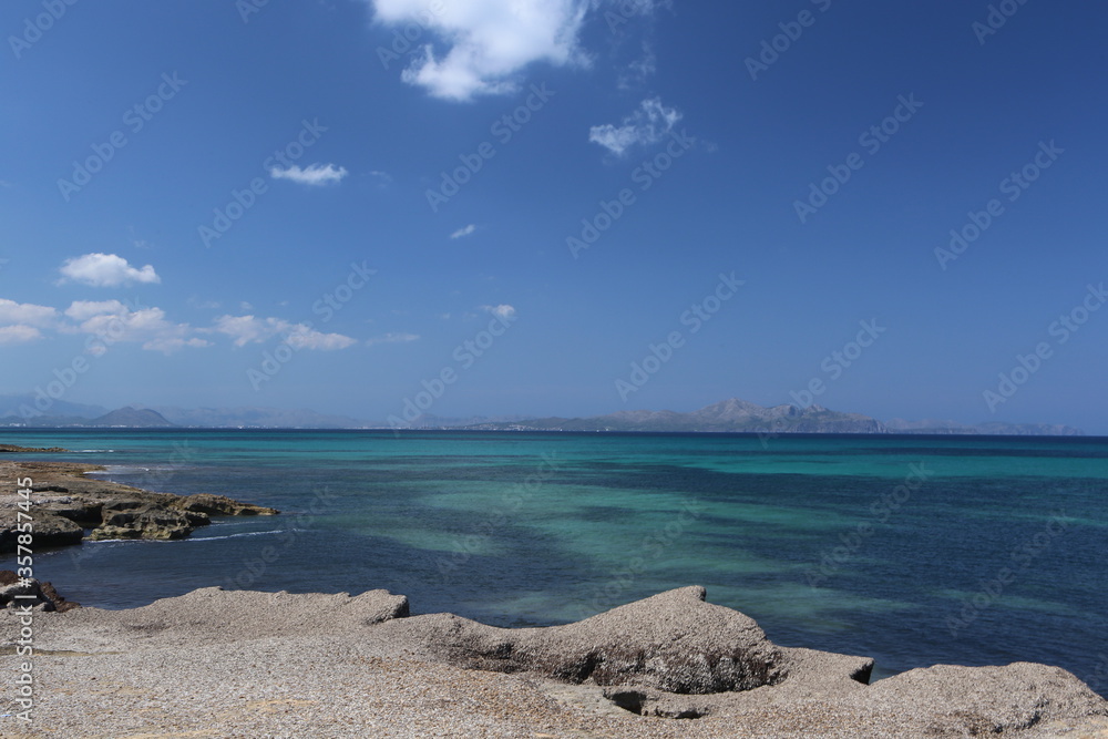 panorama landscape scenic view of isolated deserted rocky beach with blue turquoise sea water and sky with white clouds background on beautiful and colorful Mallorca island in Spain