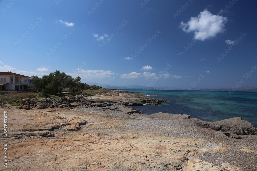 panorama landscape scenic view of isolated deserted rocky beach with blue turquoise sea water and sky with white clouds background on beautiful and colorful Mallorca island in Spain panorama landscape scenic view of isolated deserted rocky beach with blue turquoise sea water and sky with white clouds background on beautiful and colorful Mallorca island in Spain