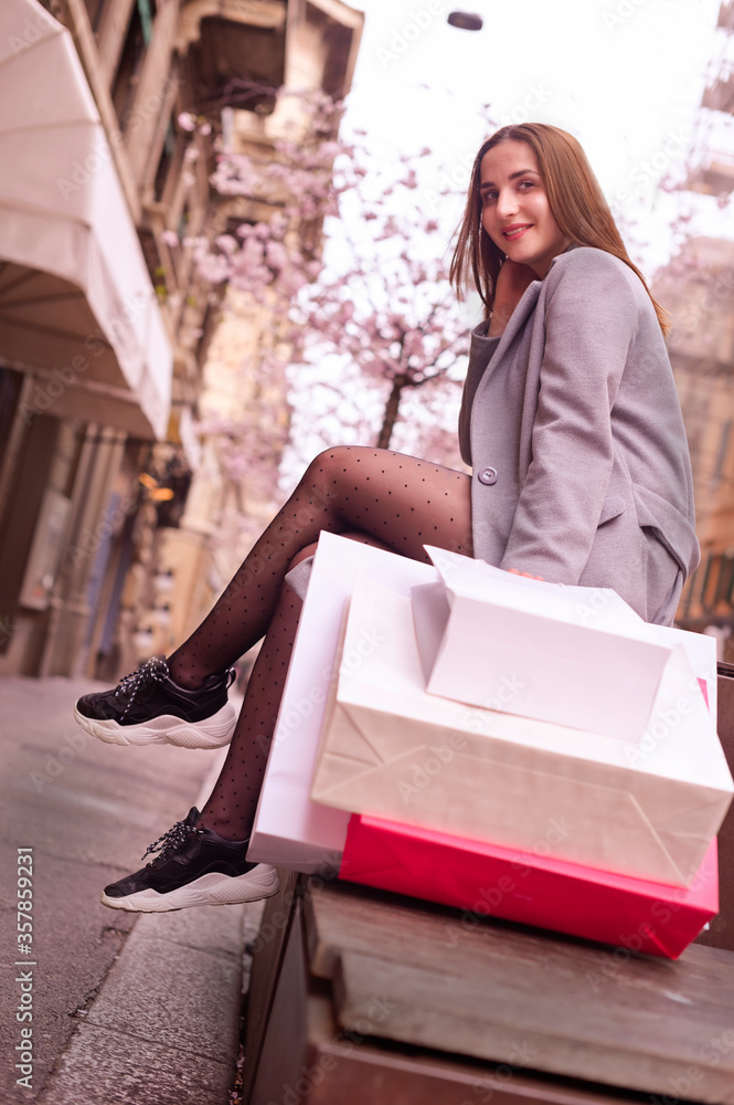 Shopping girl. Beautiful young woman with big bags of shopping in the center of the Italian city. Shows funny emotions and joy, positive emotions. Soft focus. Free space for text