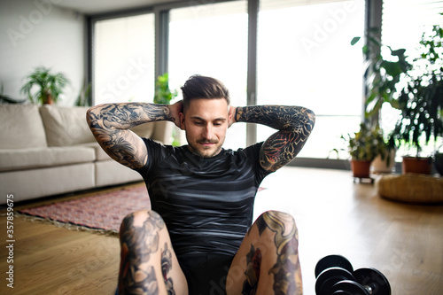 Front view portrait of man doing workout exercise indoors at home. photo