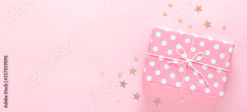 Gift box on a delicate pink background with sparkles, copy space.