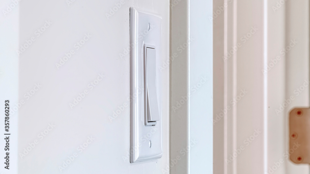 Panorama crop Side view of electrical rocker light switch mounted on white interior wall Panorama crop Side view of electrical rocker light switch mounted on white interior wall