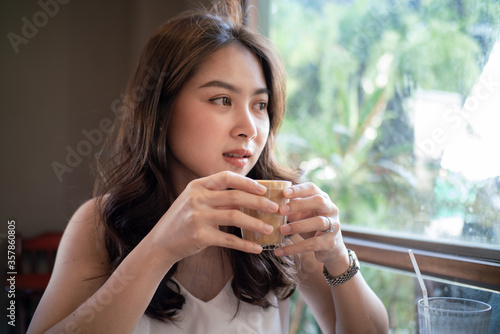 Asian women sitting in cafe drinkking hot latte
