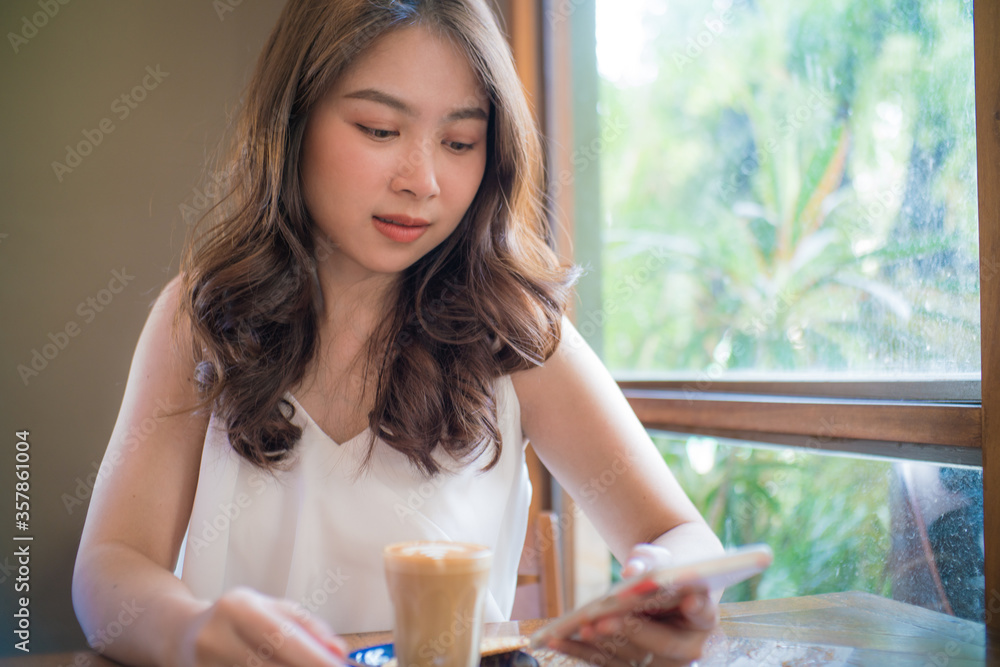 Asian women sitting in cafe drinkking hot latte Asian women sitting in cafe drinkking hot latte