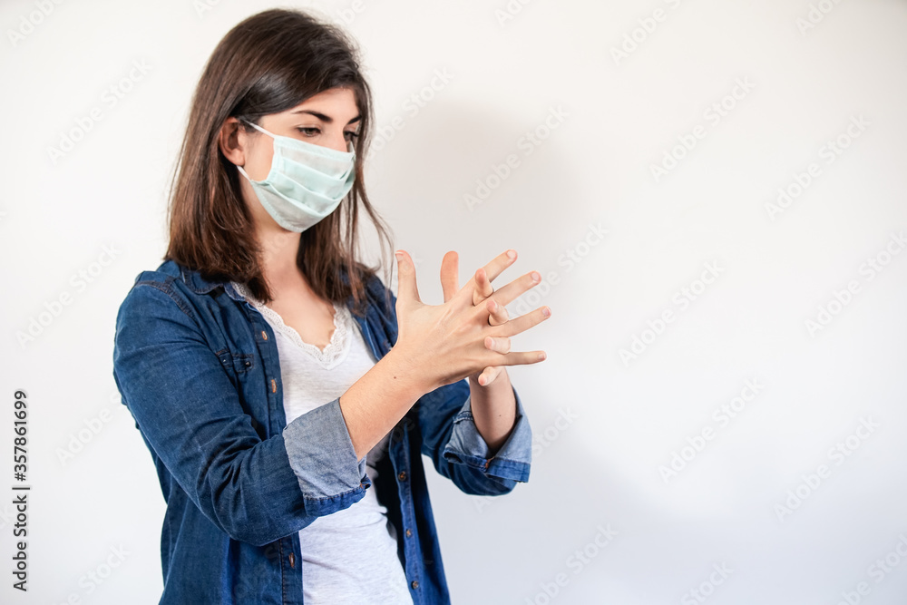 Woman with medical protection mask cleaning her hands. Woman with medical protection mask cleaning her hands.