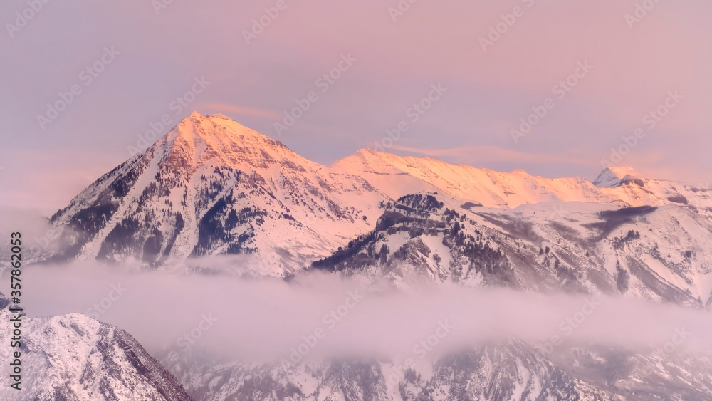 Panorama frame Snowy Wasatch Mountains with sharp peaks illuminated by sunset in winter