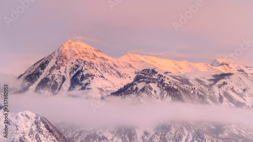 Panorama frame Snowy Wasatch Mountains with sharp peaks illuminated by sunset in winter
